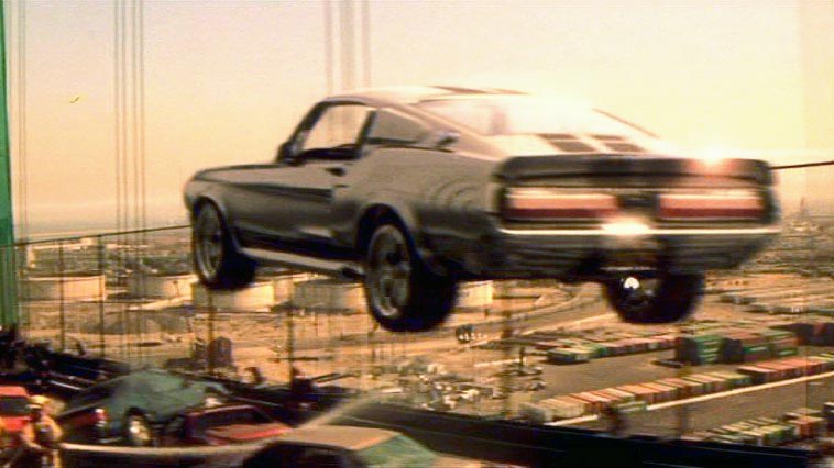 When late great film critic Roger Ebert reviewed 2000’s remake of the 1974 cult classic, he got the model of the hero car wrong but gave the movie props nonetheless; that’s a pretty  impressive feat, considering the original movie’s final chase crunched gears and burned rubber for over half an hour. The new one does it justice, though, thanks to the fact that Cage mostly drove Eleanor himself and the fantastic clutch poppin’, gear lever slammin’, tach needle pingin’ final stunt, where Cage’s Memphis Raines clears an entire traffic jam in a single bound. And outpaces a chopper (impressive, even though it’s only “an Astar, sir, not an Apache”). And navigates the streets of downtown LA… backwards, with enough time to smile and wave.