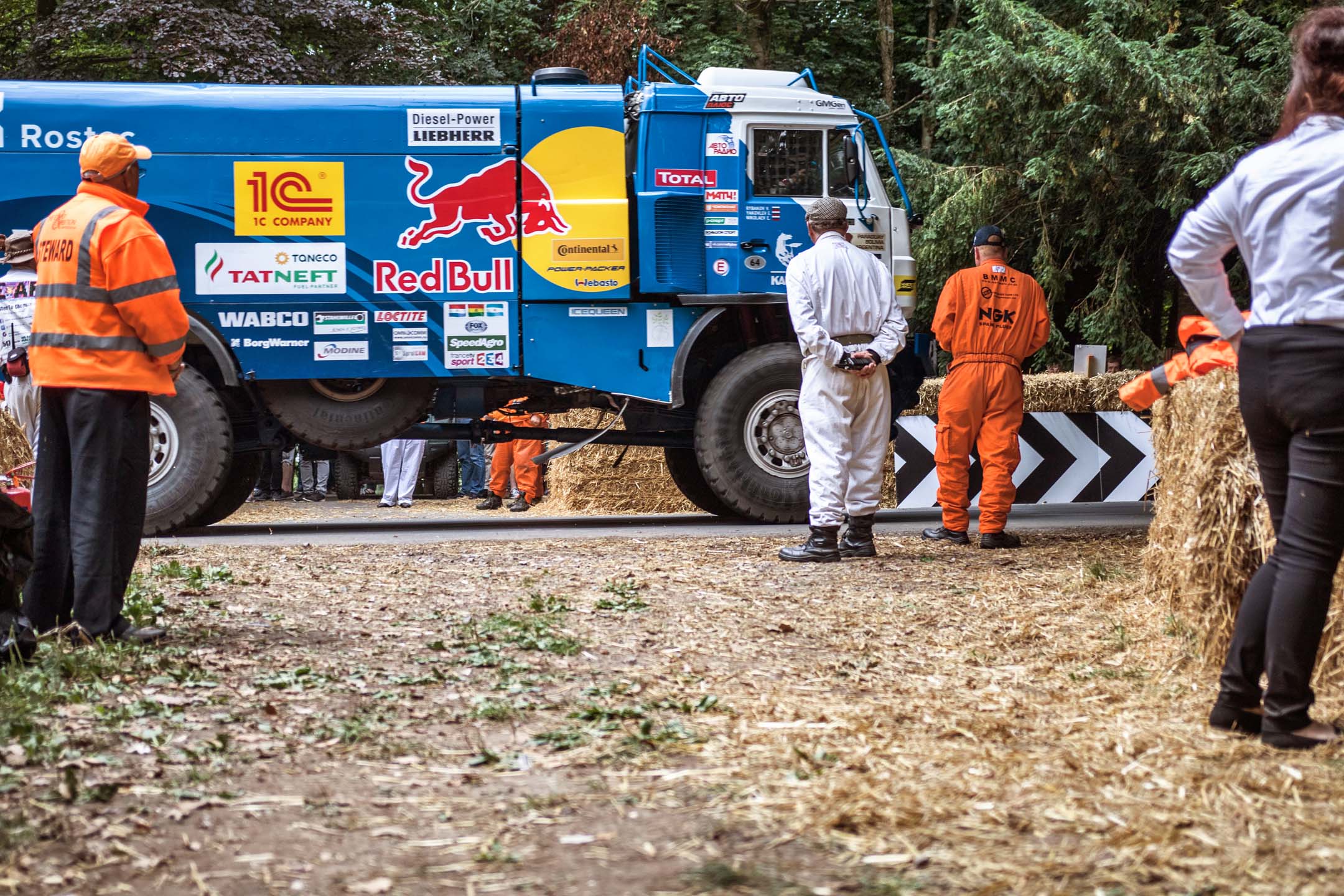 At the entry corner near the famously unforgiving flint wall, a leviathan appears. Intended for Dakar desert racing, this Red Bull-liveried truck appears in a whoosh of turbodiesel fury, then vanishes around the corner, chasing the finish line.